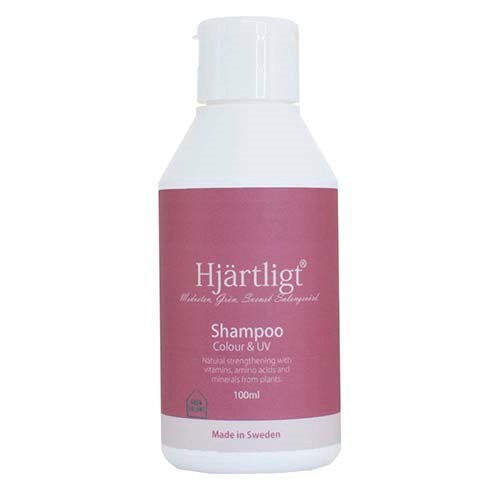 En hvid flaske med en pink etikette, der siger Hjärtligt Shampoo, lavet i Sverige, til farve og UV-beskyttelse.