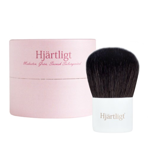 En lyserød rund boks og en stor makeuppensel med hvidt håndtag mærket 'Hjärtligt'.