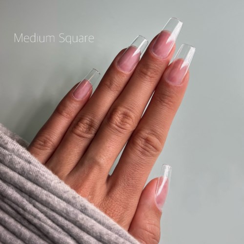 A hand with long, clear, rectangular nails, partly covered by a gray fabric sleeve.