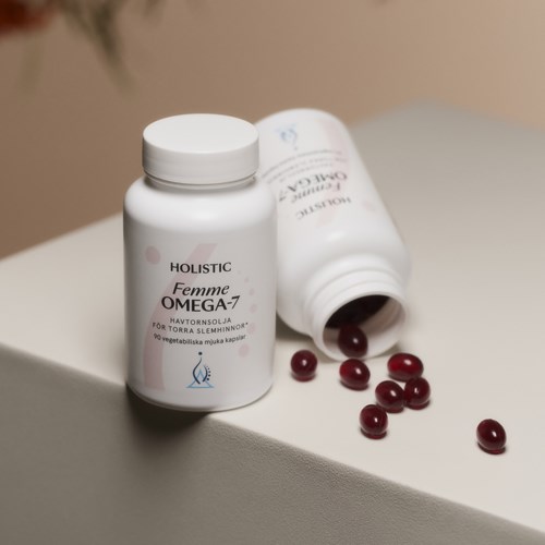 Vita kosttillskottflaskor märkt 'Holistic Femme Omega-7' med tabletter utspillda i närheten.