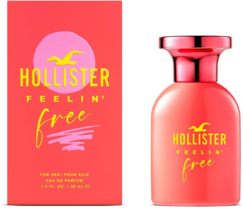 Różowa butelka perfum i pudełko z żółtym tekstem i logo mewy, reklama zapachu Hollister Feelin' Free.