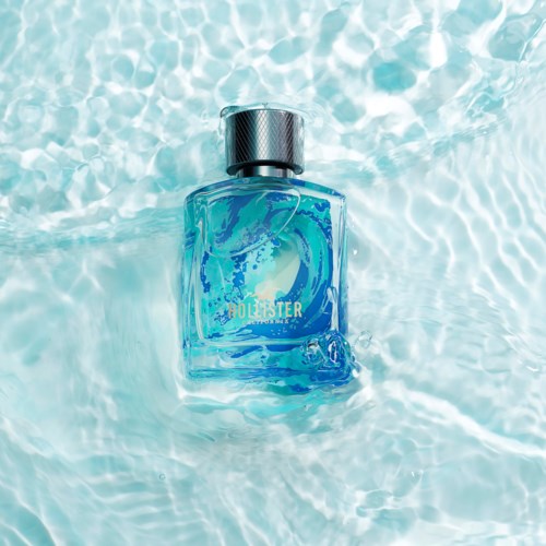 Eine blaue Parfüfflasche schwimmt im Wasser mit Sonnenreflexionen auf der Oberfläche.