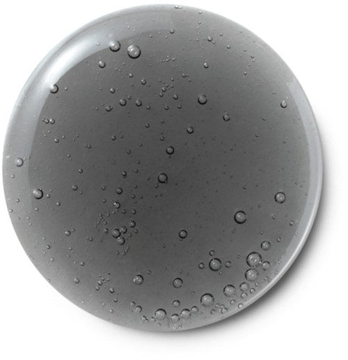 A gray, round, flat object with small bubbles inside, resembling a gel or a liquid-filled tablet.