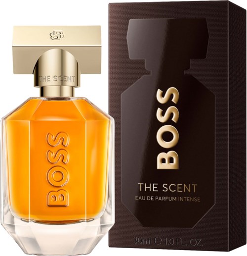 A bright orange perfume bottle with a gold label and a black box with gold text next to it.