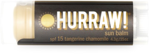 En läppbalsamrör med beige och svart färg, märkt "HURRAW!" och nämner SPF 15 samt ingredienser som mandarin och kamomill.