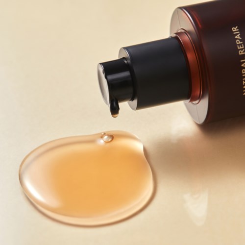 En flaska märkt 'Natural Repair' med en droppe vätska på en beige yta.