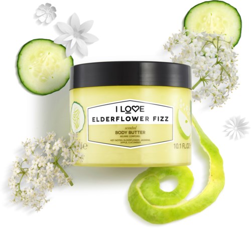 En krukke med elderflower fizz duftende kroppsbokt, omgitt av agurkskiver, elderflower-blomster og en agurkskrell.