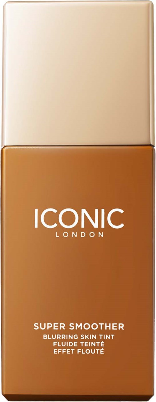 Butelka podkładu z napisem "Iconic London Super Smoother" w kolorze beżowym i brązowym, z tekstem opisującym rozświetlający podkład."}