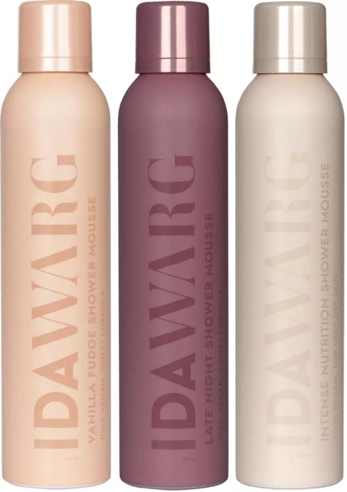Drei Flaschen Duschschaum mit unterschiedlichen Etiketten und Farben: Pink, Lila und Beige.