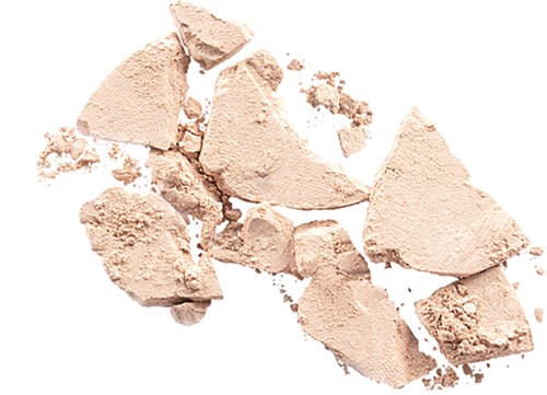 Krossat beige puder spridd på en vit bakgrund.