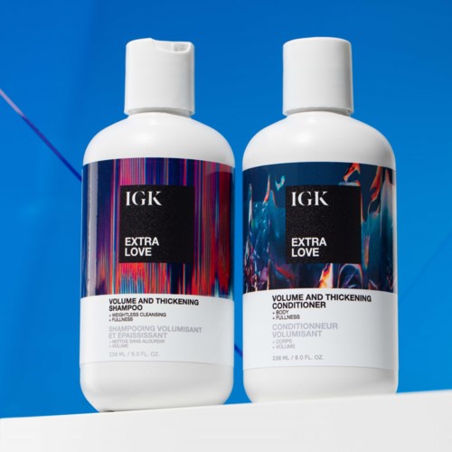 Zwei Flaschen Haarpflegeprodukte für Volumen und Verdickung, mit dem Etikett IGK Extra Love, vor blauem Hintergrund.
