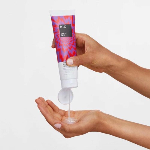 Eine Hand hält eine Tube mit Produkt, das weiße Creme in die andere offene Hand gibt.