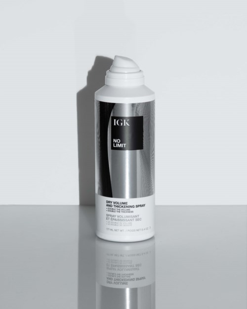 En hvit sprayflaske med svart og sølv etikett fra IGK, merket 'No Limit' og 'Dry Volume and Thickening Spray.'