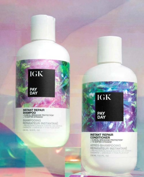 Kaksi valkoista IGK Pay Day -tuotepulloa, shampoo ja hoitoaine, värikkäillä, kiiltävillä tarroilla.