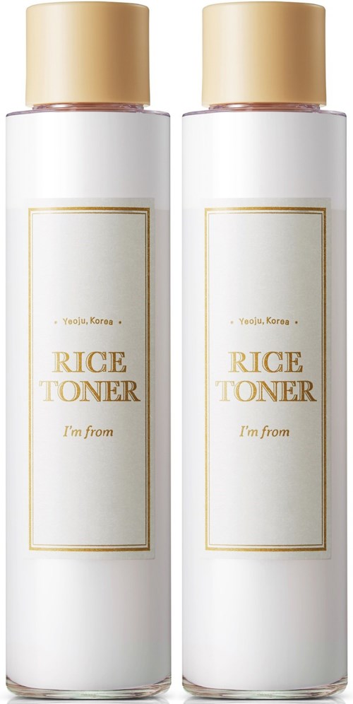 Dwie białe butelki z napisem 'Rice Toner' z beżowymi zakrętkami stoją obok siebie.