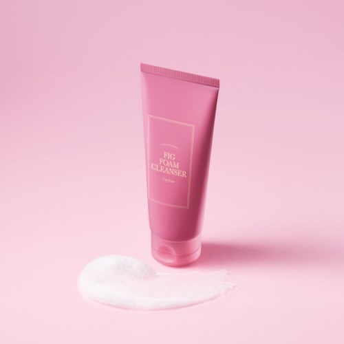 Różowa tubka z napisem 'Fig Foam Cleanser' stoi na różowym tle z pianką na powierzchni.
