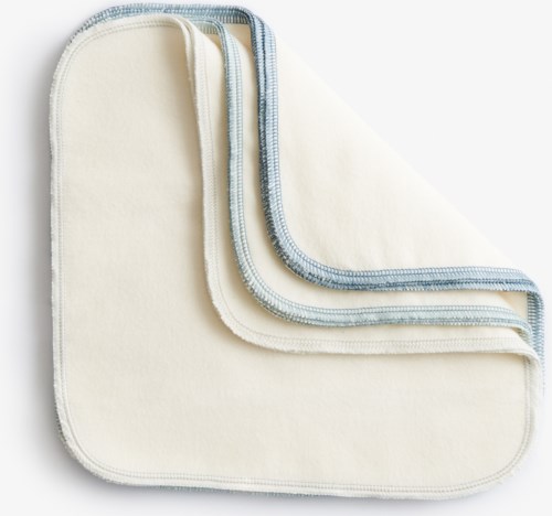 Multiple cloths with stitched edges, layered on each other, mostly white and light blue.