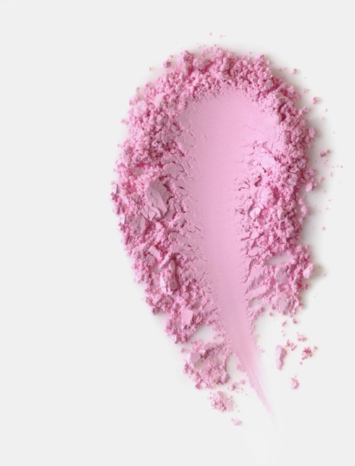 Pink powder spread out on a white surface, with some falling apart and a shadow underneath.