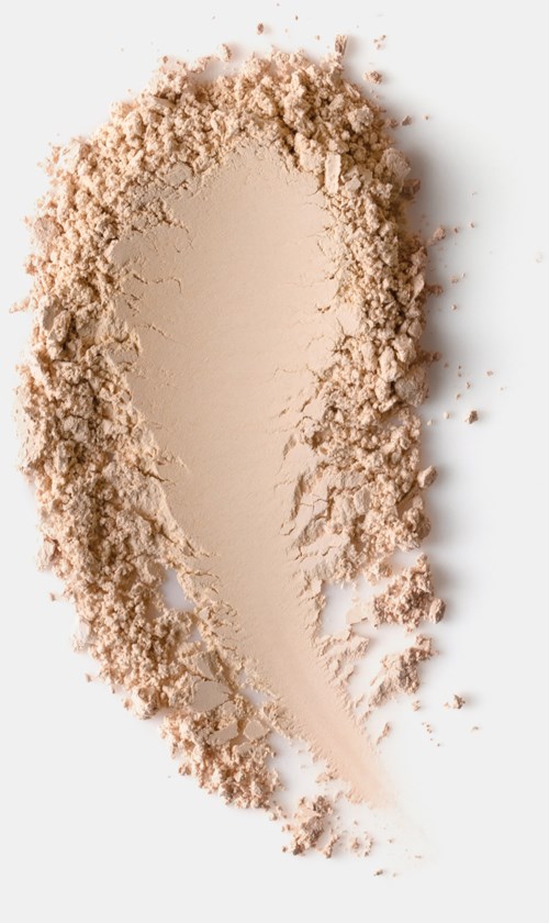 A beige powder is spread on a white background, shaped like a large, elongated smear with uneven edges.