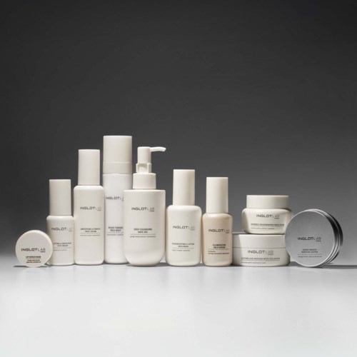 Een verzameling witte huidverzorgings- en cosmeticaproducten met verschillende flessen, potjes en containers op een grijze achtergrond.
