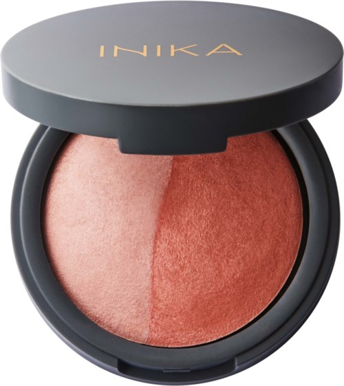 A compact blush with two shades inside, topped with a dark lid with gold text that says 'INIKA'.