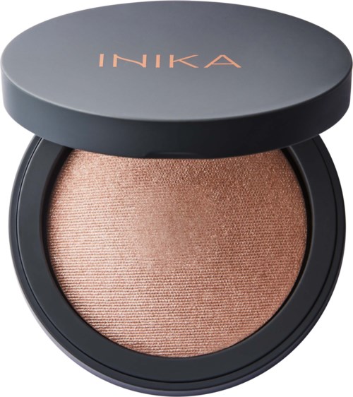 Ett kompakt med glittrande beige smink, med svart lock som visar märket INIKA.