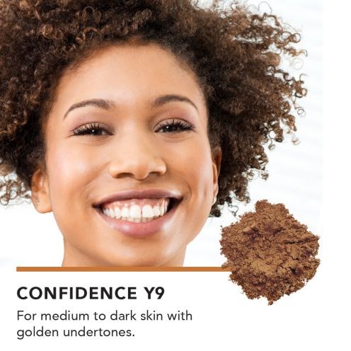 Glad kvinna med lockigt hår och klar hy, marknadsför Confidence Y9 för mellan till mörk hudton.