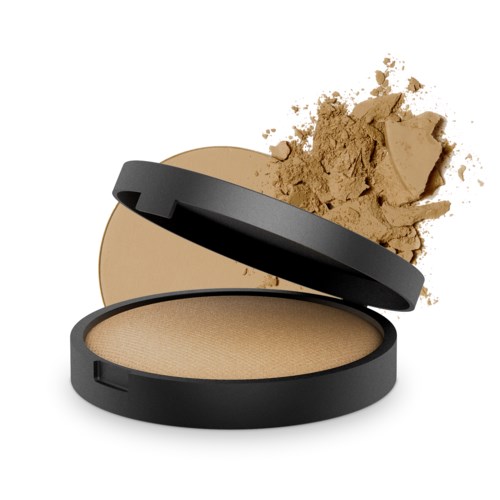 En rund liten behållare med beige puder inuti och lite pulver spilld ovanpå, i ett svart fodral.