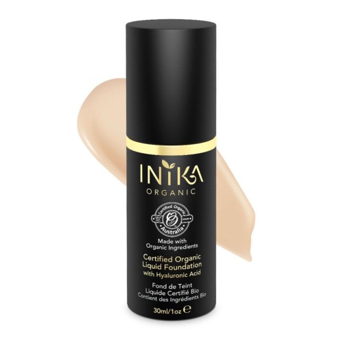 En svart flaska med ekologisk flytande foundation, med beige foundation bakom, märkt 'Intika Organic'.
