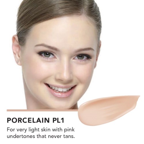 En kvinna med ljus hud och ljust brunt hår, ler, med ett prov av foundation märkt "Porcelain P1".