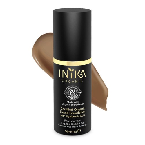 En svart flaske merket 'Inika Organic' med en beige krem bak den.