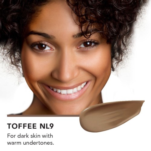 En smilende kvinne med mørk hud og krøllete hår. Bildet viser et sminkeprodukt kalt Toffee NL9 for mørk hud.