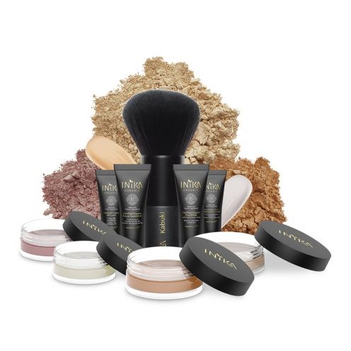 Makeup-produkter med borstar och puder, i svarta behållare med puder bakom.
