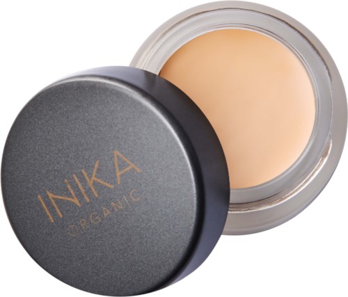 En rund glasburk med beige kräm inuti och ett svart lock märkt 'INIKA ORGANIC'.