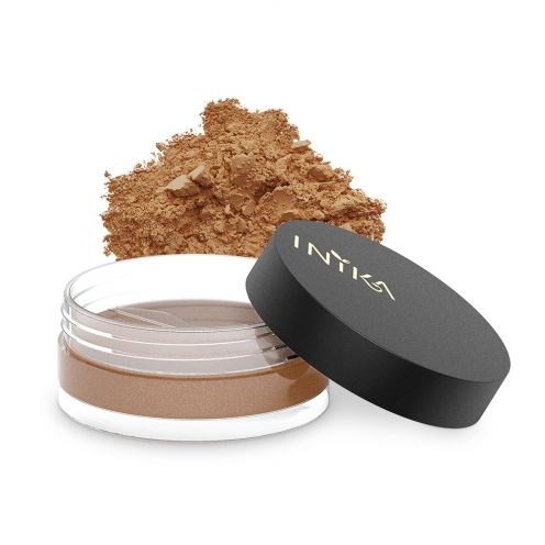 Ett kompakt puderburk med svart lock, lite löspuder och ett krossat makeuppuder i bakgrunden.