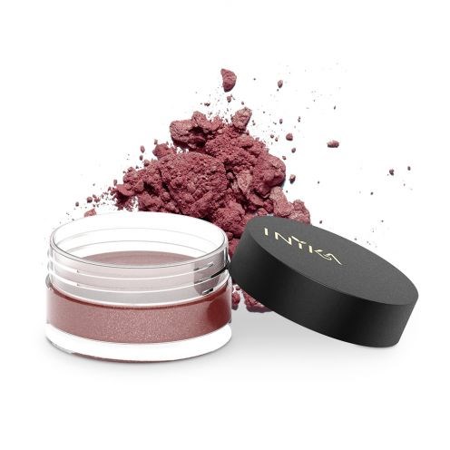 En behållare med rosa pulver bredvid dess svarta lock, med lite pulver spillt runt.