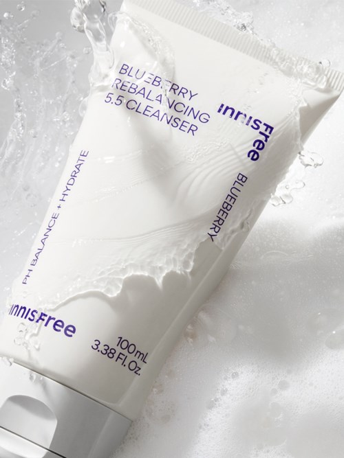 Eine weiße Tube des INNISFREE Blue Berries Rebalancing 5.5 Cleanser mit Wasser spritzend.
