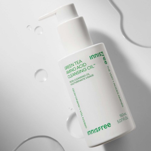 Witte fles met groen text van Innisfree Green Tea Amino Acid Cleansing Oil, op een witte achtergrond met waterdruppels.