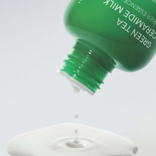 Groene fles met witte crème die eruit loopt en een kleine spetter vormt.