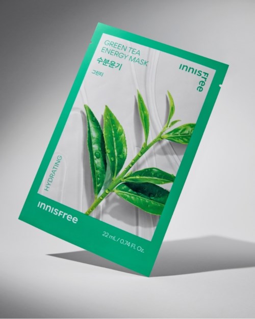 Een groen thee energie masker verpakkingsmet een bladontwerp en tekst, staand op een muur.