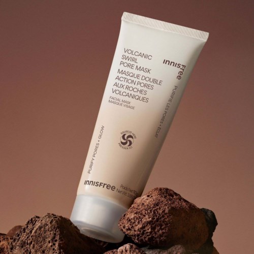 En tube Innisfree vulkansk pore maske hvilende på vulkanske steiner mot en brun bakgrunn.