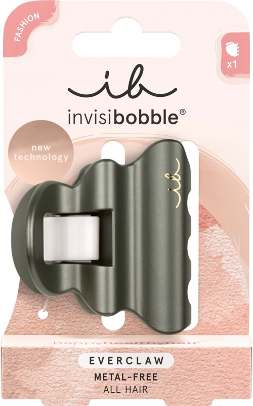 En liten svart hårklämma med vågigt design, fäst vid rosa och vit förpackning märkt 'invisibobble' och 'Everclaw'.