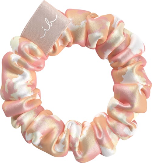 A pink and white satin scrunchie with a gray tag that has the word 'il' on it.