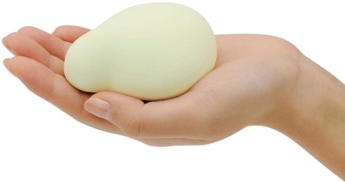 En hånd holder et stort, hvitt, ovalt objekt, kanskje et egg eller noe mykt.