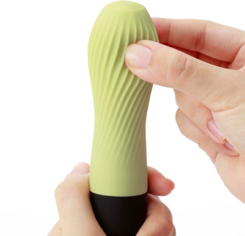 En person holder i et grønt, spiralformet silikonobjekt med en svart base, som klemmes mellom fingre.