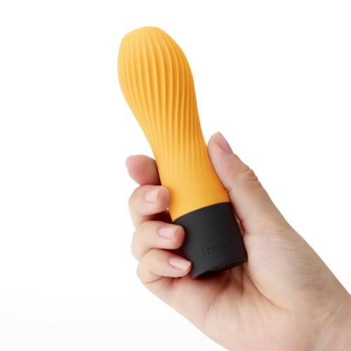 En hand håller i ett gult, ribbat, äggformat föremål med en svart bas.