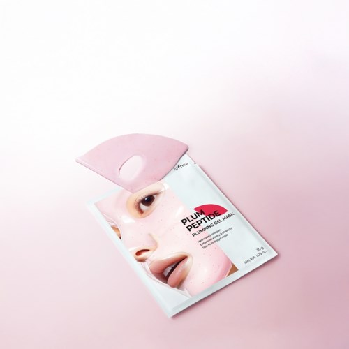 Et ansiktsmaskepakke med ansiktsbilde og rosa emballasje, plassert på lyserosa bakgrunn.