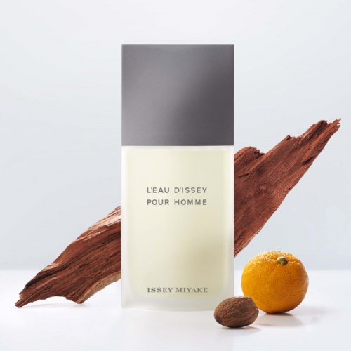 A men's perfume bottle with a simple design, a piece of wood, an orange, and a nut. 
