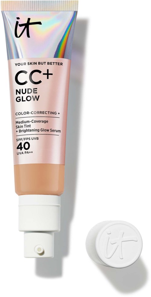 En tub med IT CC+ Nude Glow foundation med lock bredvid, med en glänsande, regnbågsliknande bakgrund och rosa förpackning.