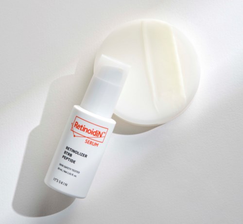 En liten vit flaska märkt Retinoid Serum bredvid en rund vit burk med grädde inuti.